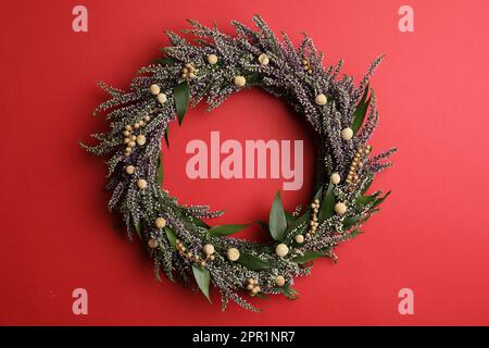 Belle couronne de bruyère sur fond rouge, vue de dessus. Fleurs automnales Banque D'Images