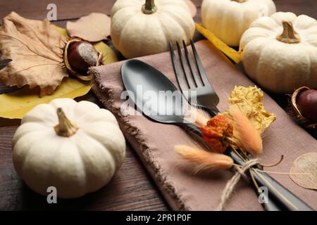 Table d'automne, clôture, coutellerie avec citrouilles et feuilles mortes sur table en bois Banque D'Images