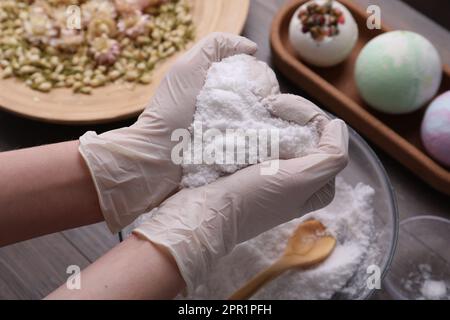 Femme en gants tenant le mélange de bombe de bain à table, gros plan Banque D'Images