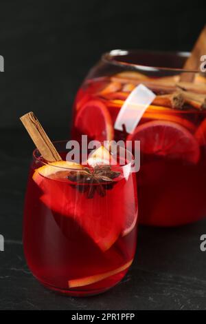 Verre et bol de délicieux punch aromatique sur table noire Banque D'Images