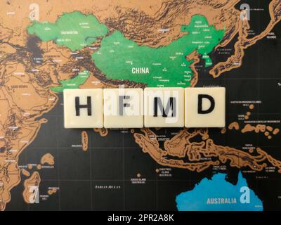 Vue de dessus jouets mot avec le mot HFMD sur un fond de carte du monde. Banque D'Images