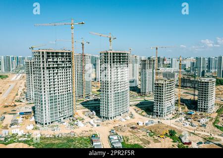 immeubles d'appartements en hauteur en construction avec grues sur fond ciel bleu clair. vue aérienne. Banque D'Images