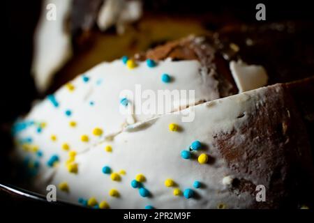 Gros plan sur le gâteau de Pâques en tranches. Glaçage blanc doux et poudre décorative colorée Banque D'Images