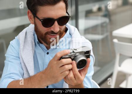 Homme avec caméra dans un café extérieur. Passe-temps intéressant Banque D'Images