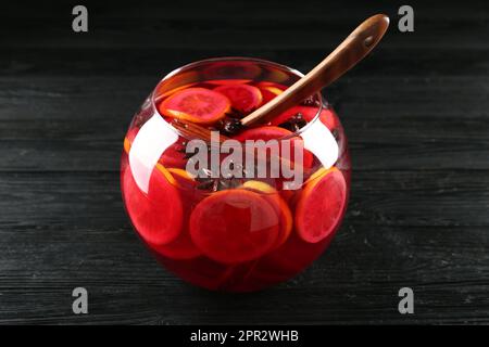 Bol en verre de délicieux punch aromatique et louche sur une table en bois noir Banque D'Images