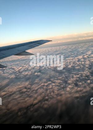 Vue de dessus de la terre depuis le hublot, les fenêtres de l'avion sur l'aile avec des moteurs, des turbines et des nuages de pluie blancs moelleux. Banque D'Images