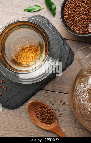 Tasse de thé de sarrasin aromatique fraîchement préparé et granulés sur table en bois, plat Banque D'Images