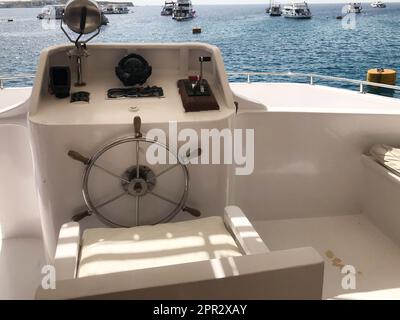 Cabine du capitaine sur un navire, un bateau, un paquebot de croisière avec un volant, un tableau de bord avec un compas de mer et des instruments pour le contrôle contre la mer bleue et Banque D'Images