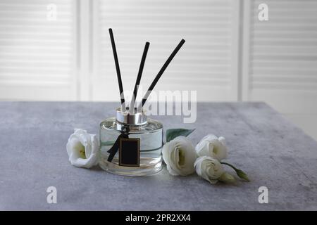 Diffuseur de roseau et fleurs d'eustoma sur une table en marbre gris Banque D'Images