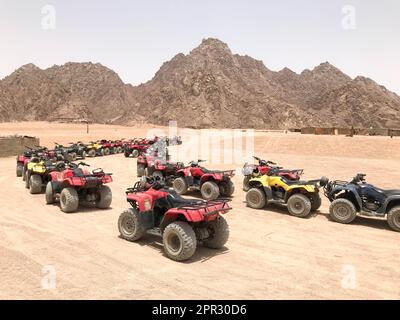 De nombreux VTT tout-terrain rapides à quatre roues, des motos dans le désert sablonneux chaud sur motosafe, se rassemblent contre les hautes montagnes. 05/ Banque D'Images