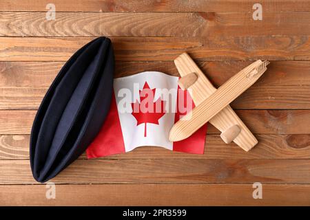 Drapeau du Canada avec chapeau d'hôtesse et jouet d'avion sur fond de bois Banque D'Images