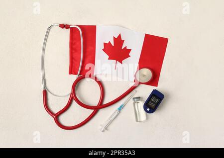 Drapeau du Canada avec stéthoscope, seringue, ampoule et glucomètre sur fond blanc Banque D'Images