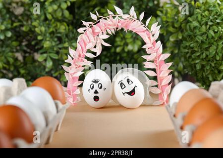 Œufs avec des visages dessinés comme mariée et marié sous l'arche décorative sur la table pendant le mariage Banque D'Images