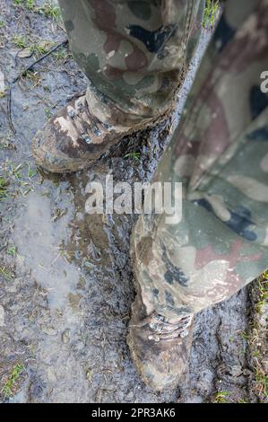 Les bottes tactiques du soldat sale après les exercices dans la boue. Banque D'Images