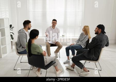 Psychothérapeute travaillant avec un groupe de personnes toxicomanes à la séance de thérapie à l'intérieur Banque D'Images