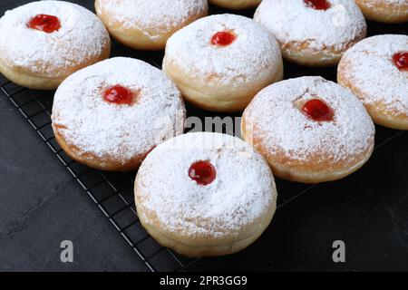 Beaucoup de délicieux beignets avec gelée et sucre en poudre sur table noire Banque D'Images