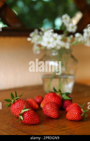 Fraises fraîches mûres et bouquet de belles fleurs sur table en bois, en gros plan Banque D'Images