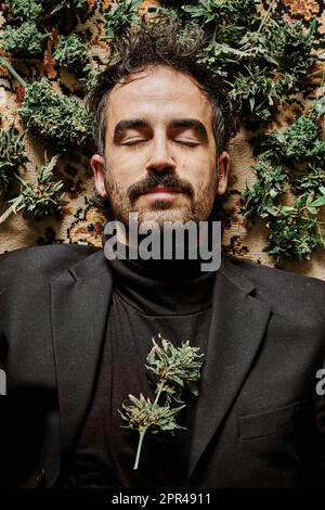 un jeune homme exécutif entouré de bourgeons de marijuana et appelant à la légalisation du cannabis. Concept de médicament Banque D'Images