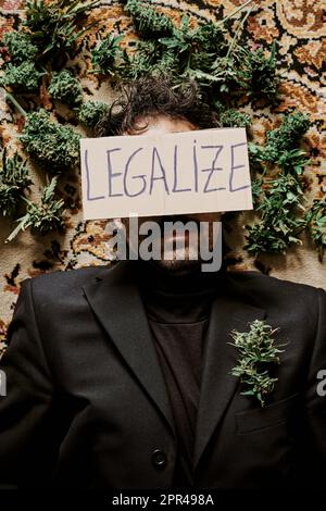 un jeune homme exécutif entouré de bourgeons de marijuana et appelant à la légalisation du cannabis. Concept de médicament Banque D'Images