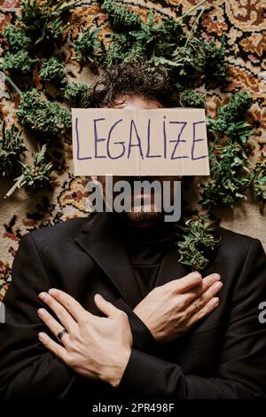 un jeune homme exécutif entouré de bourgeons de marijuana et appelant à la légalisation du cannabis. Concept de médicament Banque D'Images