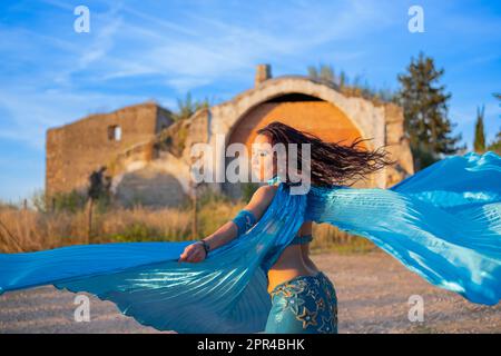 Danseuse orientale vêtue de bleu avec des ailes d'Isis de la même couleur, dansant à l'extérieur Banque D'Images