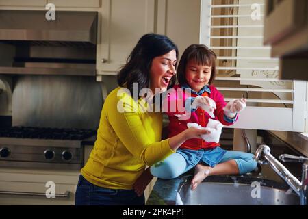 Bien propre et amusant. une jeune mère et sa fille jouant près de l'évier de cuisine. Banque D'Images