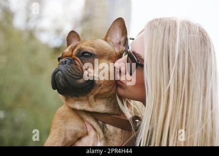 Belle jeune femme embrassant son chien. Propriétaire aimant donnant à son animal un baiser Banque D'Images