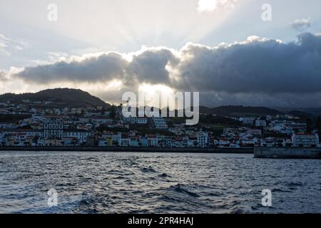 Le soleil se couche derrière les nuages au-dessus de la ville de Madalena, île de Pico, Açores, Portugal Banque D'Images