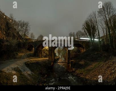 Train de nuit traversant un viaduc au-dessus de la rivière Sett dans les Torrs à New Mills, Derbyshire. Chemin de fer traversant la campagne anglaise. Banque D'Images