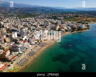 Vue aérienne d'une plage animée dans la station balnéaire populaire de Nea Chora à Chania, Crète (Grèce) Banque D'Images