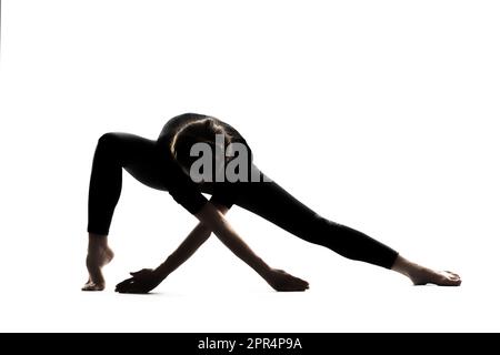 Une femme dans une asana de yoga pose avec ses bras étendus sur un fond blanc Banque D'Images