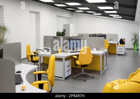 Bureau informatique avec espaces de travail pour les employés développeurs avec chaises jaunes et ordinateurs. Banque D'Images