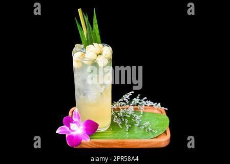 Eau de coco avec graines de lotus sur plaque en bois isolée sur fond noir Banque D'Images