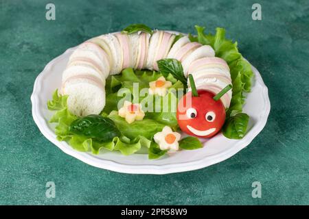 Sandwich Caterpillar amusant avec saucisse et fromage pour les enfants déjeuner sur fond vert Banque D'Images