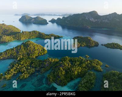 La lumière du matin brille sur les spectaculaires îles de calcaire qui s'élèvent du paysage marin magnifique, biodiversifié et varié de Raja Ampat. Banque D'Images