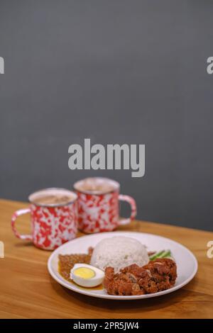 Portrait ou photo verticale d'une assiette de Nasi Lemak avec deux tasses de thé. Arrière-plan flou. Banque D'Images