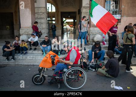 Un homme âgé avec un casque sur un fauteuil roulant duquel le drapeau italien vole vu pendant la démonstration. Environ 10 mille manifestants ont participé au défilé organisé par l'ANPI (Association nationale des partisans d'Italie) à Rome à l'occasion du 78th anniversaire de la libération du fascisme nazi. En partant de Largo Bompiani, ils ont traversé les quartiers de Tor Marancia, Garbatella et Ostiense, jusqu'à leur arrivée à Porta San Paolo. La manifestation s'est terminée à Piazzale Ostiense par des discours de personnalités politiques, de syndicats et par les témoignages de ceux qui étaient par Banque D'Images