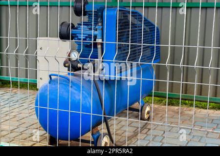 Compresseur mobile avec moteur électrique et grand récepteur de cylindre. Équipement spécial pour l'aire de jeux. Peint en bleu. Gros plan. Mise au point sélective. Banque D'Images