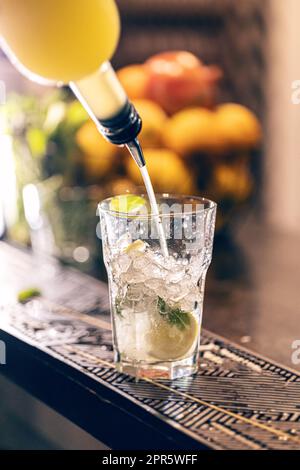 Barman versant du sirop dans un verre à cocktail Banque D'Images