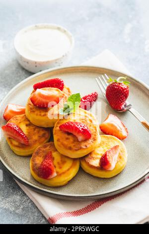 Crêpes au fromage cottage, beignets de ricotta ou syrniki à la menthe et aux fraises. Petit déjeuner sain et délicieux. Banque D'Images