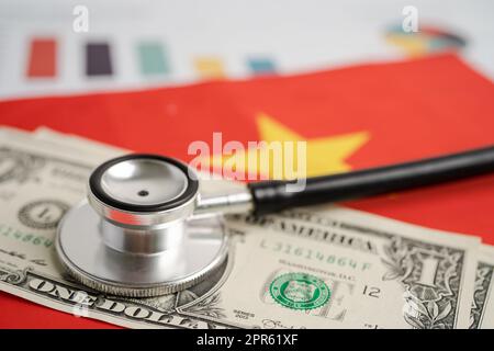 Stéthoscope noir sur fond de drapeau du Vietnam avec graphique, concept d'affaires et de finances. Drapeau de fond avec des billets en dollars américains, Business et finance concept. Banque D'Images