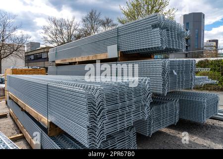 Longue grille en métal gris empilée en piles sur un chantier de construction Banque D'Images