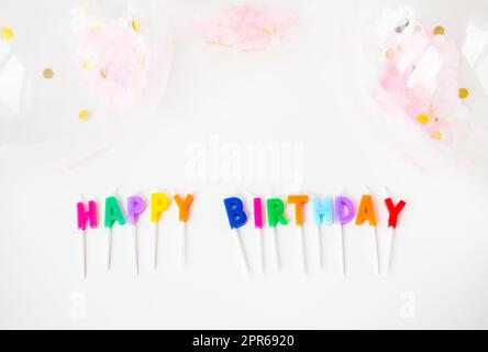 Bougies colorées avec l'inscription Joyeux anniversaire isolé sur fond blanc avec confetti. Concept de vacances et de surprise. Banque D'Images