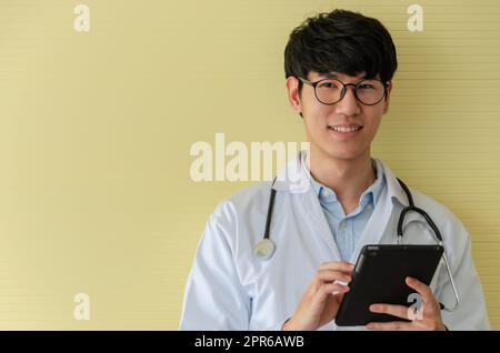 Jeune médecin en uniforme blanc utilisant un Tablet PC et regardant la caméra Banque D'Images