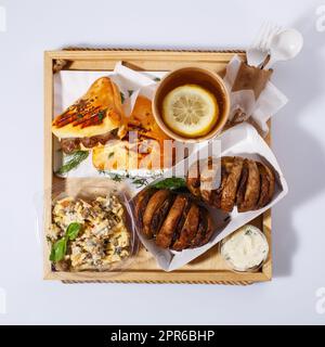 Cuisine de rue. Thé au citron, salade, pommes de terre cuites à la viande, sauce et petits pains à saucisse au romarin. Vue de dessus. Banque D'Images