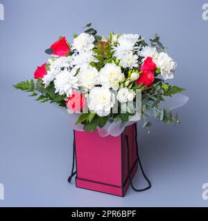 Magnifique bouquet dans une boîte cadeau rose est posé sur un fond bleu. Banque D'Images