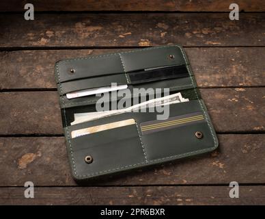 Portefeuille vert en cuir avec argent et cartes de crédit sur fond de bois ancien Banque D'Images