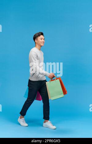 Pleine longueur photo de l'homme heureux beau regardant des vêtements élégants aller galerie marchande vide espace tenir les achats de transport Banque D'Images