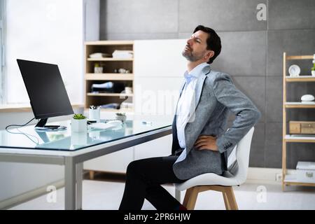 Mauvaise posture assise au bureau avec mal de dos Banque D'Images