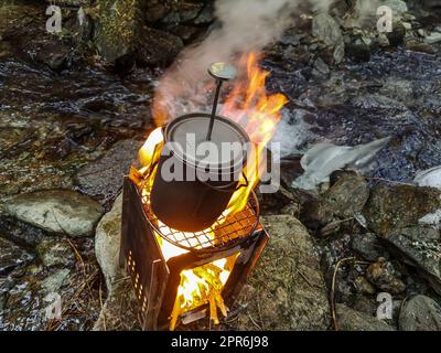 faire bouillir de l'eau au-dessus d'un feu ouvert Banque D'Images